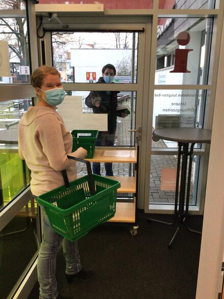 Lena Fritsche zeigt gemeinsam mit ihrem Kollegen Dennis Marggraf am Windfang der Zweigstelle in Salzgitter-Bad wie Medien kontaktlos übergeben werden.