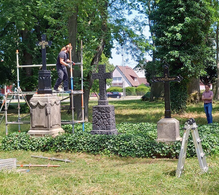 Adrian Sievers sieh Andreas Müller beim Aufbau der Grabkreuze zu.