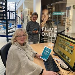 Spaß beim Filmeschauen – mit dem Leseausweis und einem Computer geht das einfach: Sylvia Fiedler, Leiterin der Stadtbibliothek, (stehend) und ihre Vertreterin Barbara Henning präsentieren die Vielfalt.