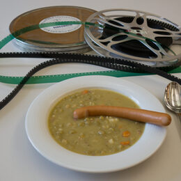 Zwei Filmrollen und eine Teller mit Erbsensuppe und Würstchen